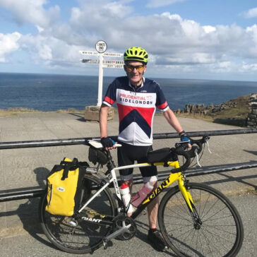 Richard standing with his bicylcle at Land's End by the sign to John o'Groats