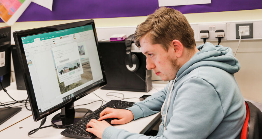 Young man sat in a classroom using a computer
