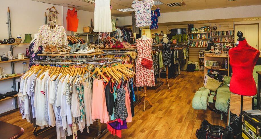 inside of a charity shop with lots of rails of clothes