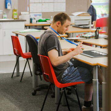 Male student sat on red chair in classroom