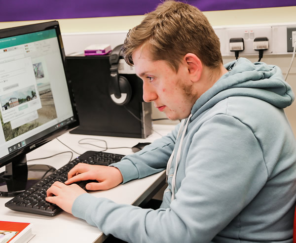 Young man sat in a classroom using a computer
