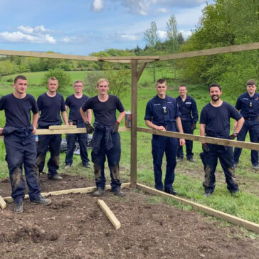 Group of Royal Navy submariners in uniform posing underneath a timber structure in the countryside