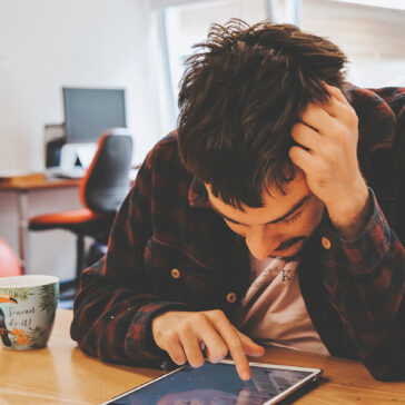 Young man leaning over a table working on an iPad