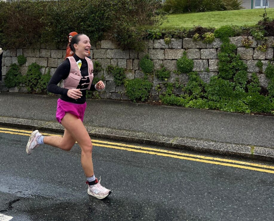 Young woman runs energetically along road in an running event.