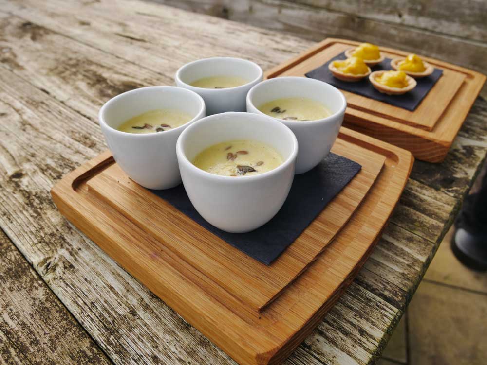Close up of the soup appetiser in four small cups, with the four tartlets behind.