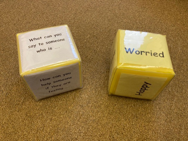 Two dice are labelled with different emotions. One reads 'what can you say to someone who is' and the other reads 'Worried'.