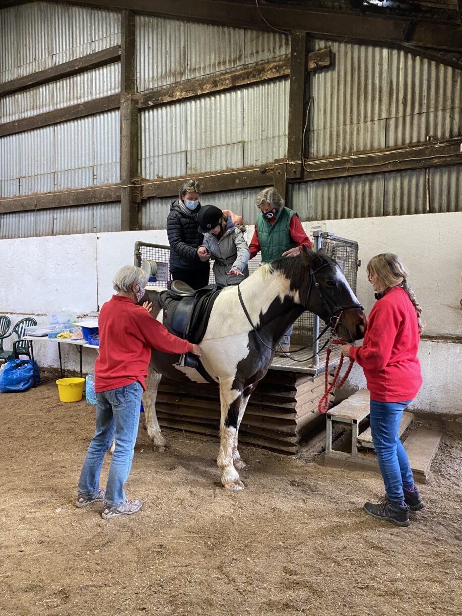 A young women being supported onto a horse