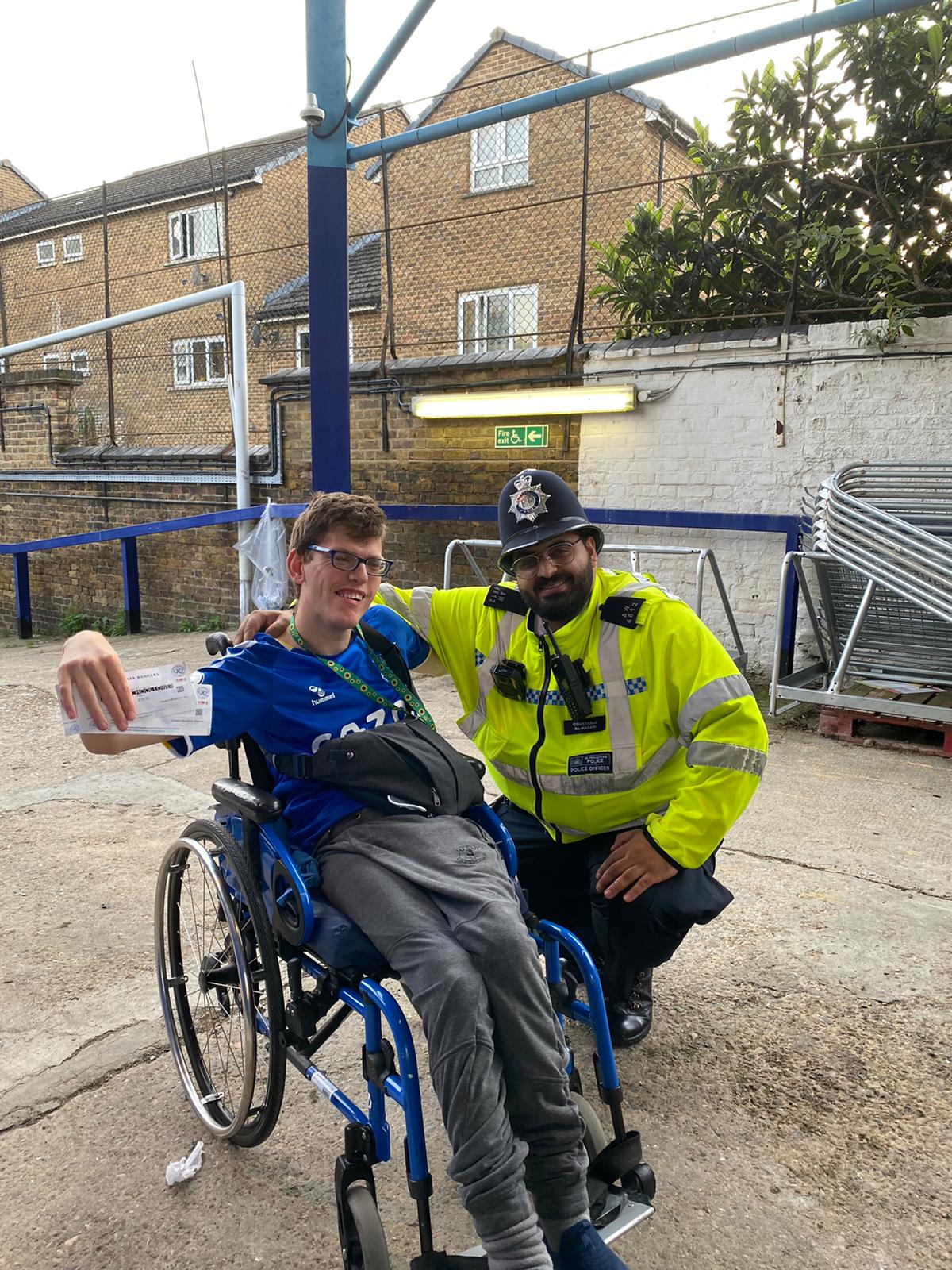 Will is holding his football tickets. A police officer is next to him for the photo. 