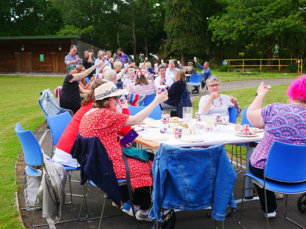 Long row of tables. Everyone's holding up their glasses in a toast