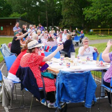 Volunteers from InFocus sitting at tables outside and raising a glass