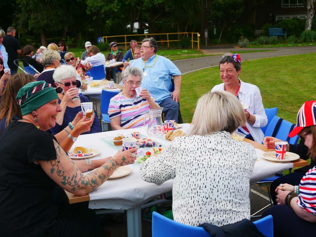 Group of smiling people sitting outside at a table.