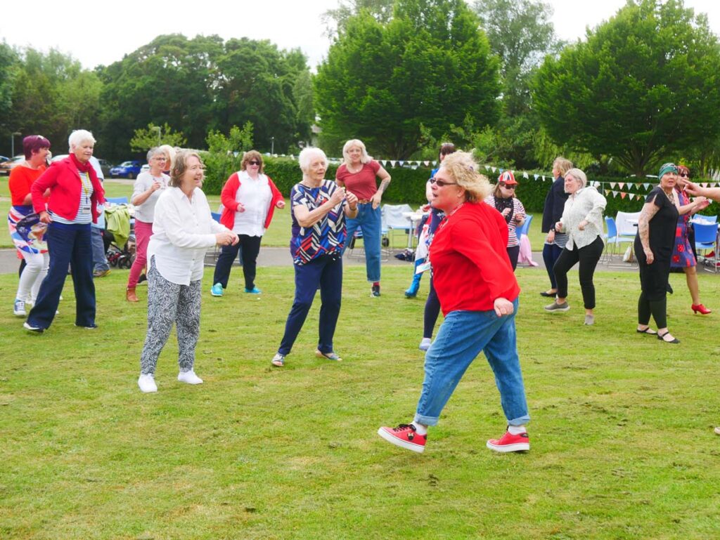 Group of people in rows dancing outside on the lawn