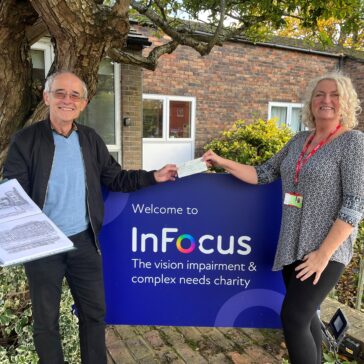 Former pupil, Aubone, is pictured with Sue Serret, our Head of Fundraising. Aubone is holding some of his art and they are both smiling.