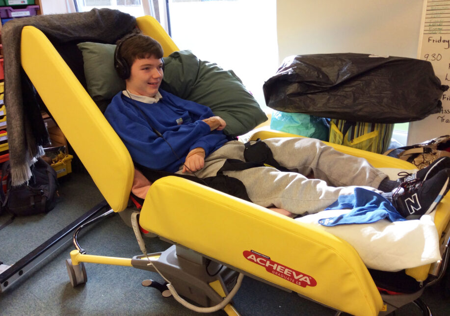 A boy lying on an Acheeva bed. He's wearing headphones and is smiling.