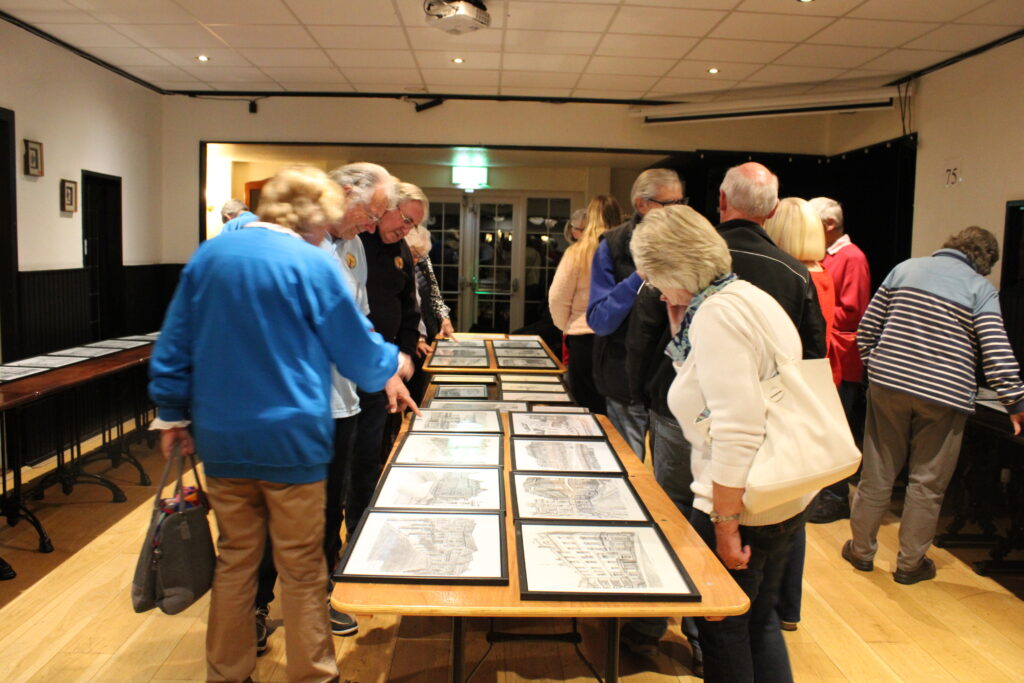 A group of people are gathered around a long table displaying Aubone's art.