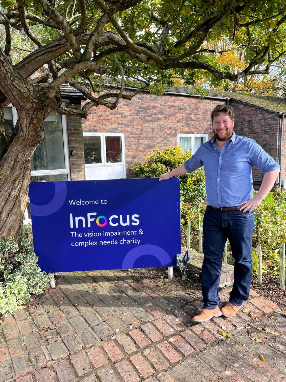 Fundraiser Peter poses for photo against the InFocus sign on campus.