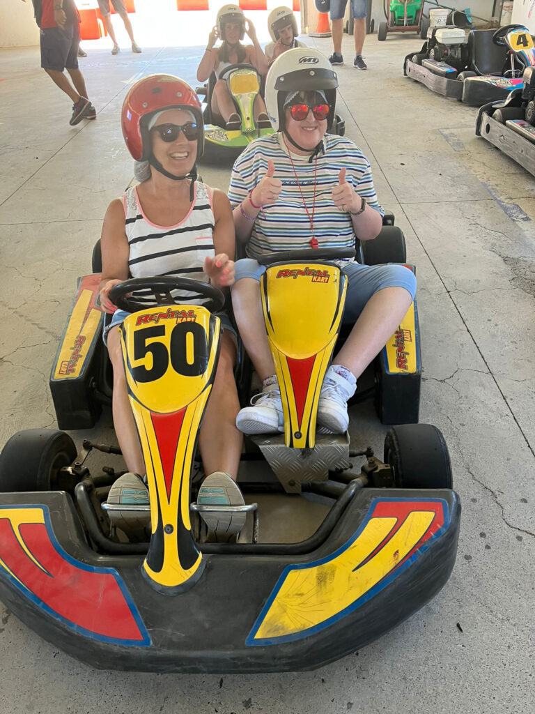 Student and member of staff looking excited on a go-kart.