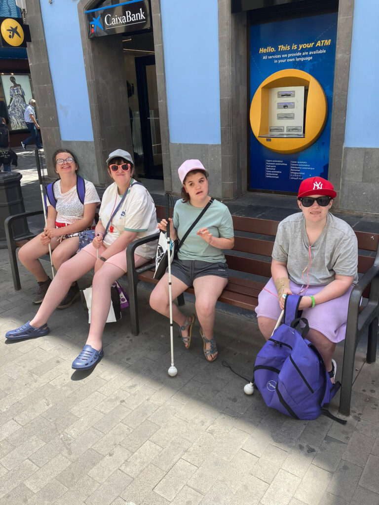 Four students sitting on a bench in the shade in Gran Canaria