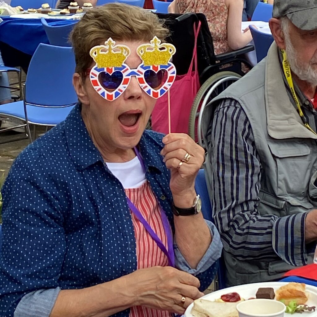 A lady holding up a pair of union jack glasses