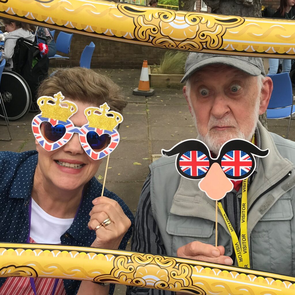 A man and a women posing for a photo through a blow up frame