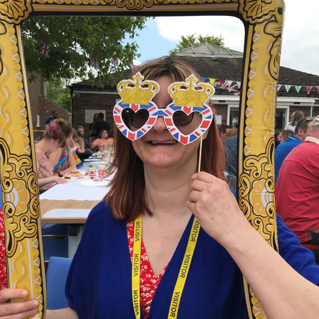 A woman posing for a photo through a blow up frame.