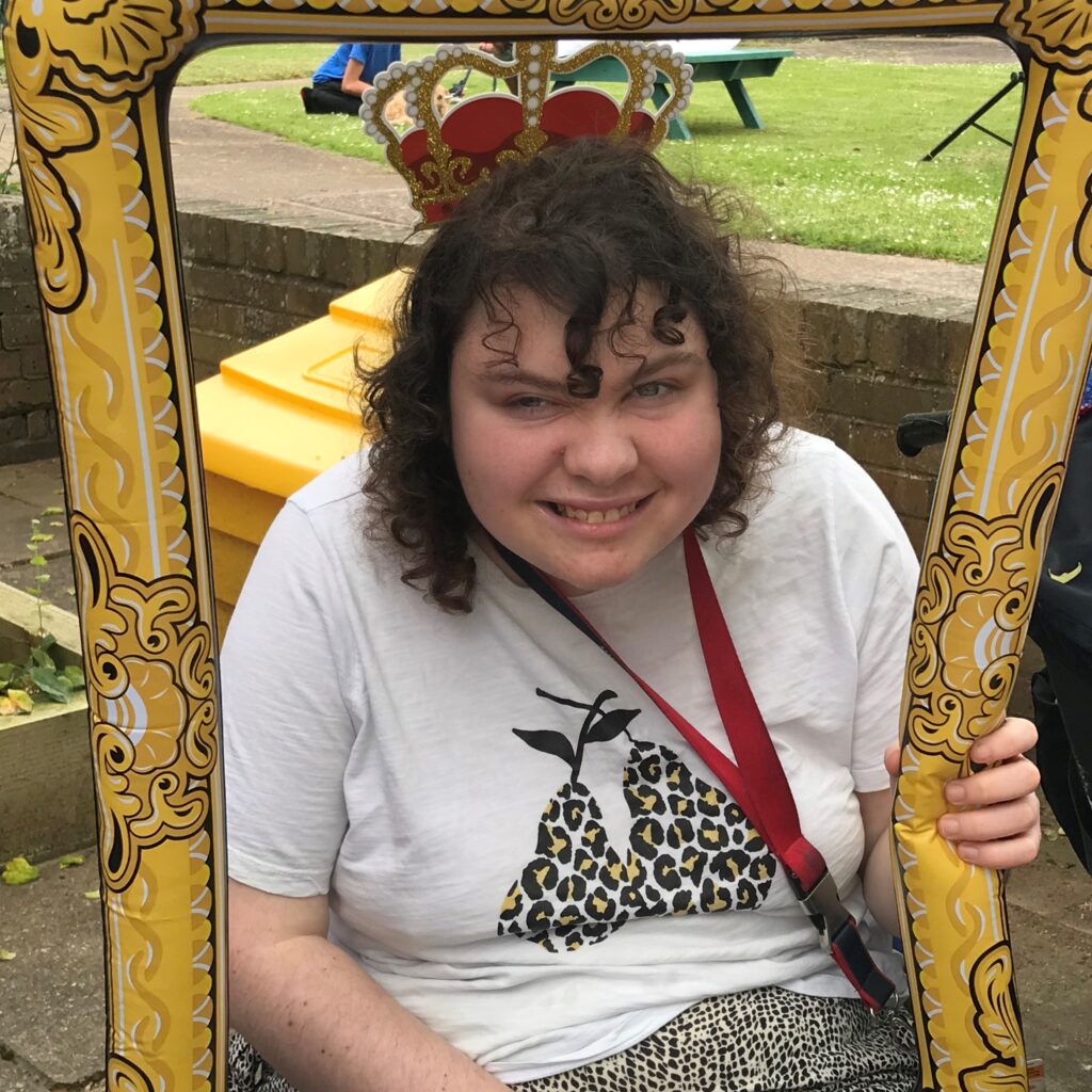 A young person posing for a photo through a blow up frame