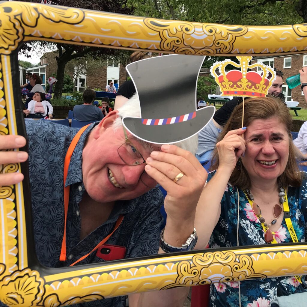 A man and a woman holding cardboard cut out hats - they're surrounded by a blow up frame.