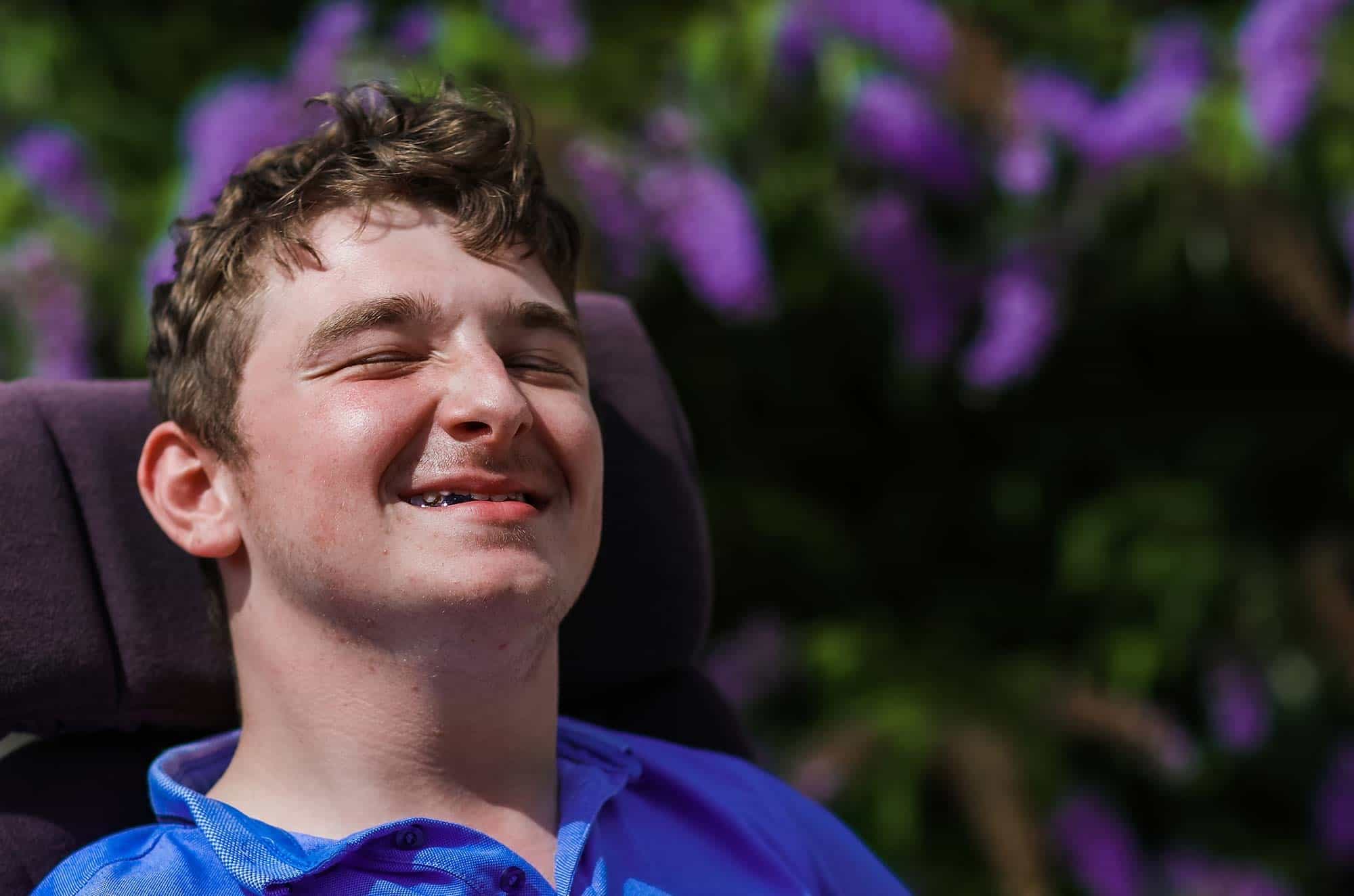 Young man in wheelchair in a blue shirt smiling