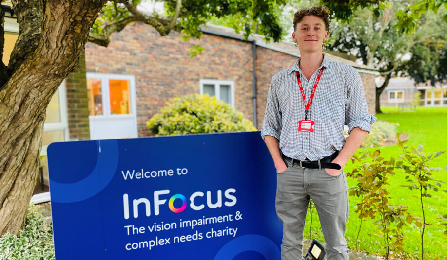 a portrait of a man stood next to the InFocus welcome sign. He's looking at the camera and has his hands in his pocket.