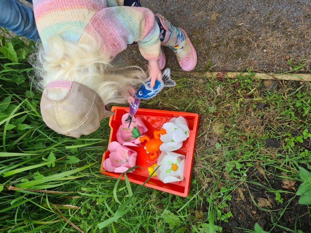 A young girl interacting with a plastic fish.