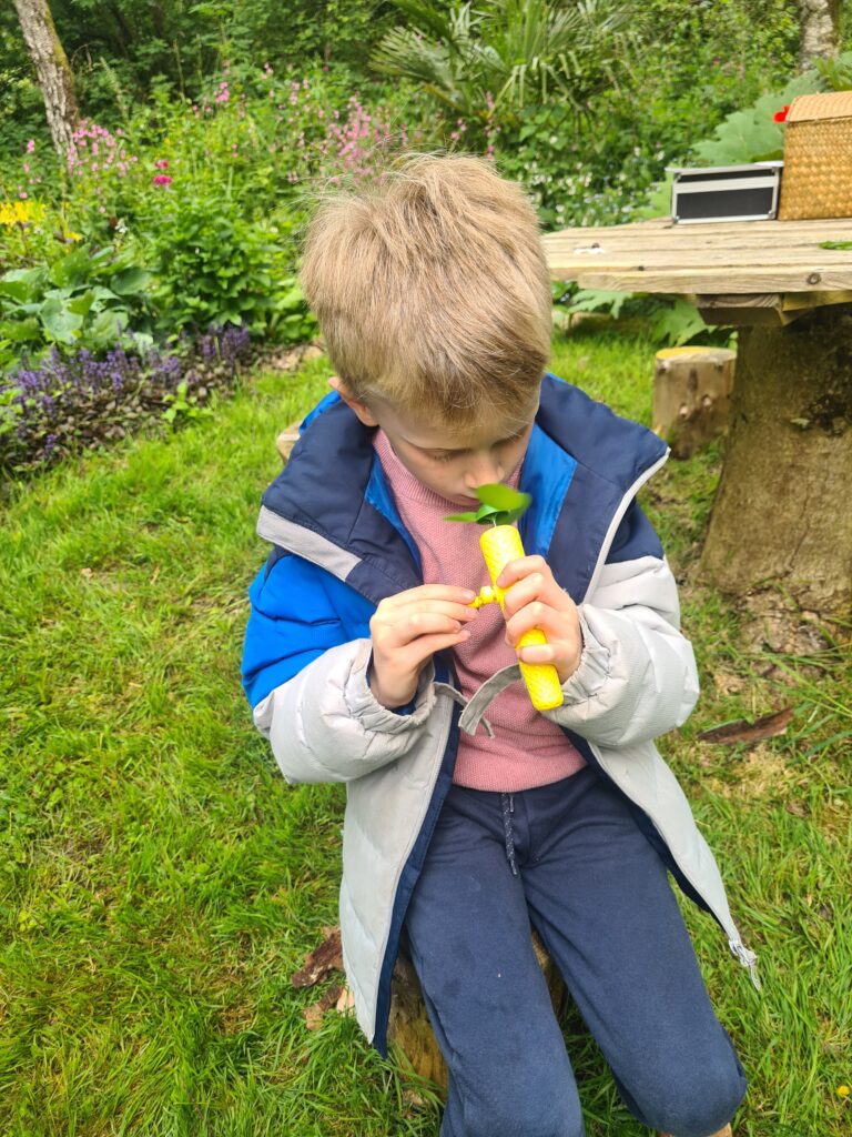 A boy is smelling something in a tube.