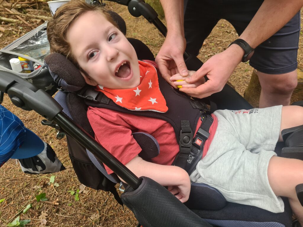 A young child is holding a small object with the help of another set of hands.