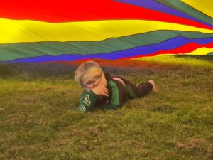 a young boy lies under a parachute.