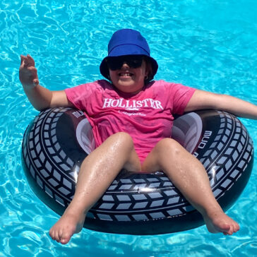 A young lady sat in a rubber ring in a pool