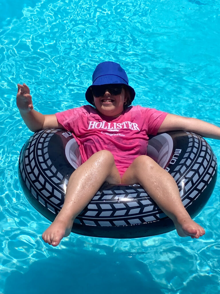 A young lady sat in a rubber ring in a pool