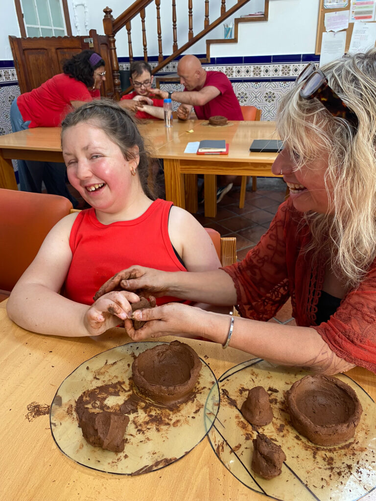 A young woman and a woman playing with clay. Both are laughing.