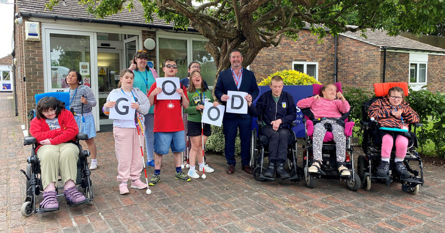 A group of students and the principal of the College - they are holding letters that spell 'good'.