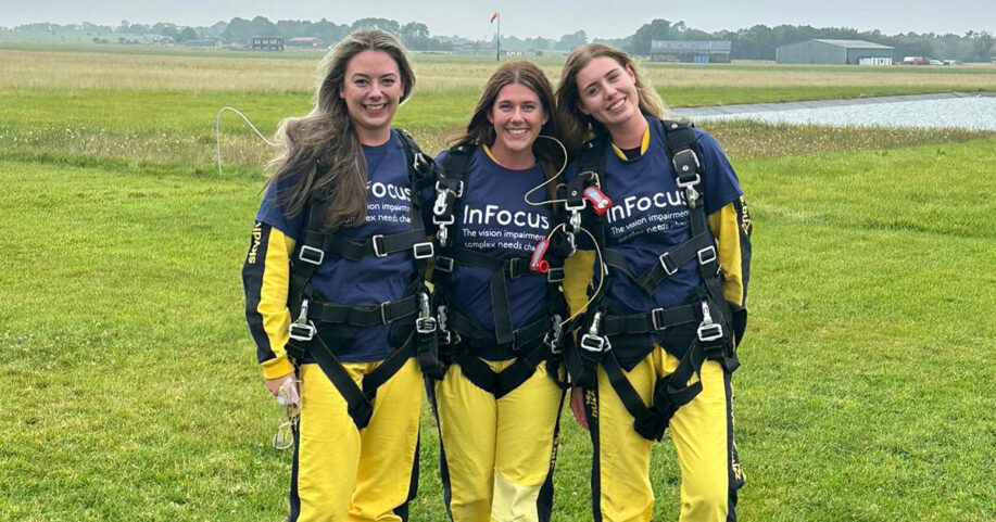 Three women stood in a field, dressed for a skydive.