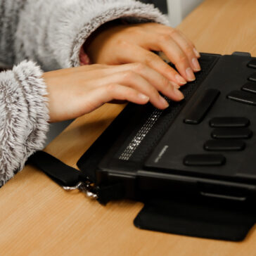 A close up photo of hands using a Braille machine.