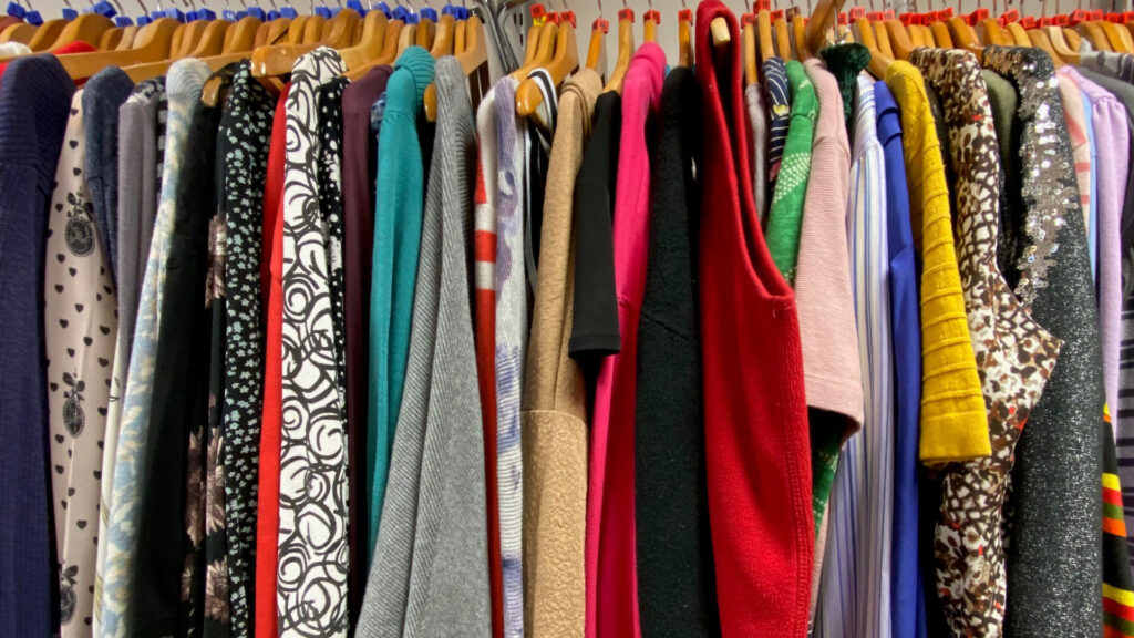 A row of brightly coloured clothes hanging on a rail.