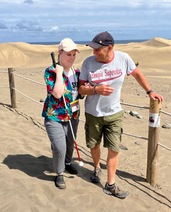 a student and member of staff walking along a beach