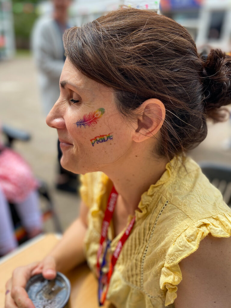 a member of staff with Pride tattoos on her face