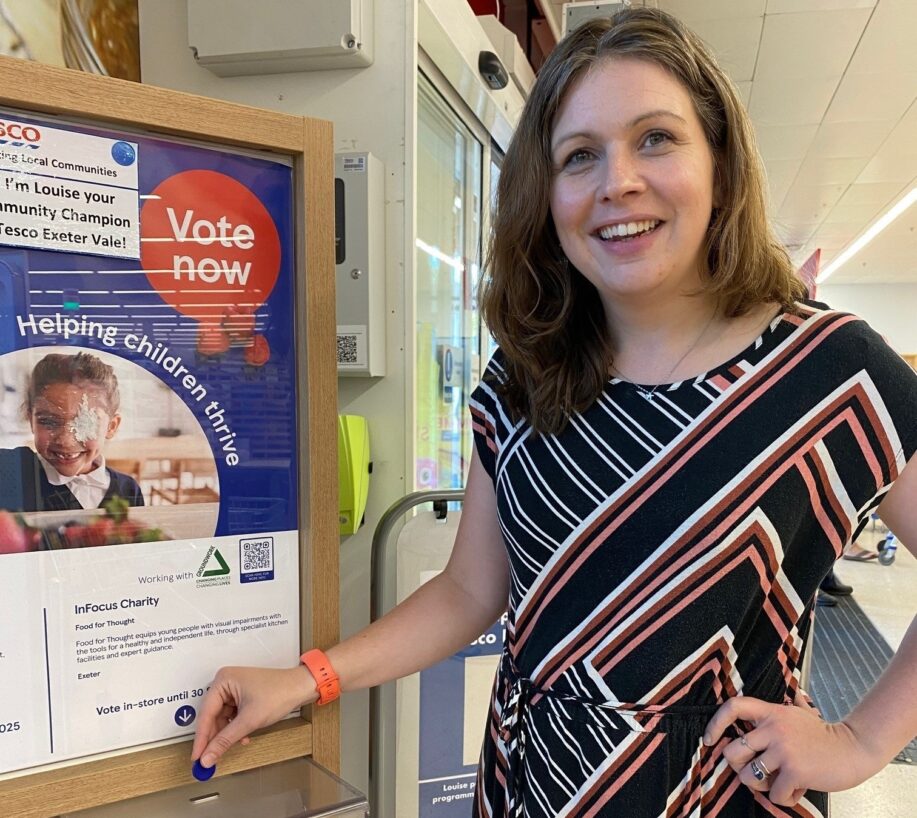 Woman dropping blue token into Tesco Stronger Starts charity box.