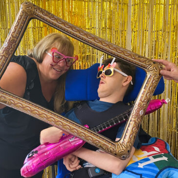 Two people in a photo booth. They're wearing fun glasses