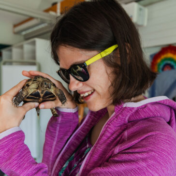 A young woman holding a small tortoise