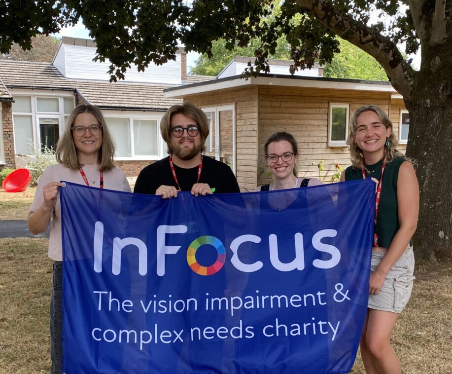 four staff members holding a flag with the infocus logo on