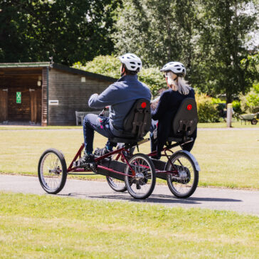 Two people cycling on a tandem around a track