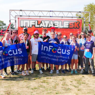 A group of runners pose with two large infocus charity banners.