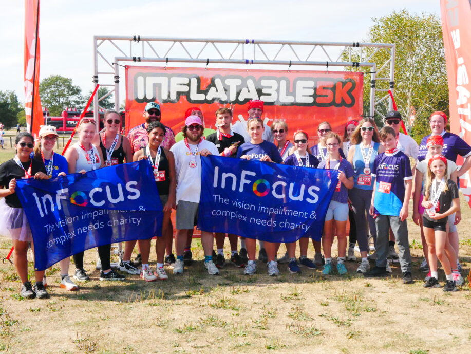 A group of runners pose with two large infocus charity banners.